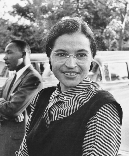 Rosa Parks with glasses standing next to MLK in background