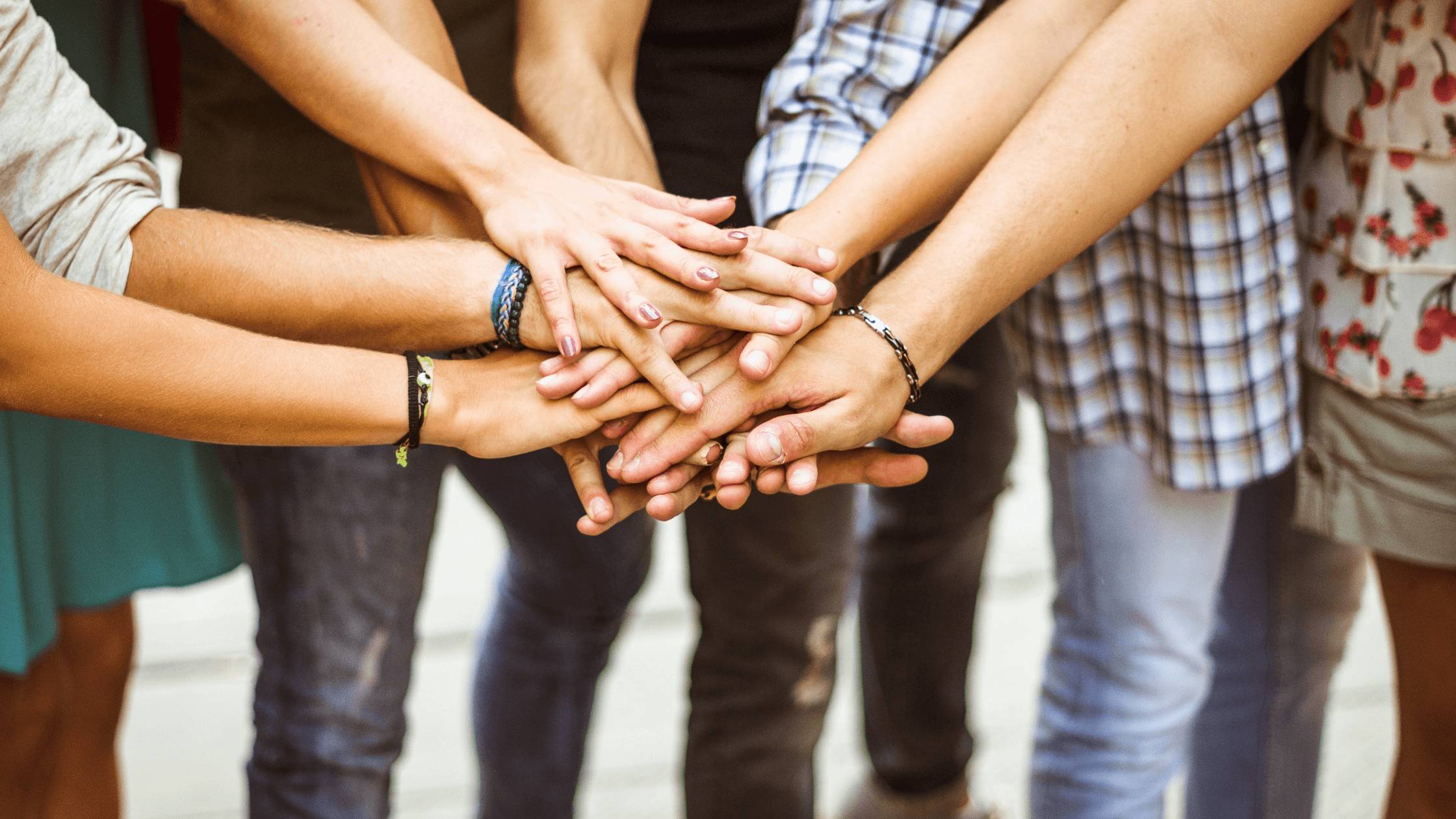 people with hands on top of each other's hands in middle